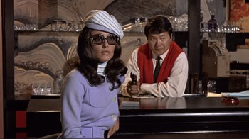 Movie still from “The Wrecking Crew” (1968), directed by Phil Karlson – A woman wearing a hat and sunglasses sitting at a bar; Medium shot, Low angle