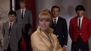 Movie still from “The Wrecking Crew” (1968), directed by Phil Karlson – A woman standing in front of a group of men; Medium shot, Low angle