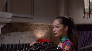 Movie still from “The Wrecking Crew” (1968), directed by Phil Karlson – A woman in a colorful shirt is holding a chocolate cake; Medium shot, Low angle