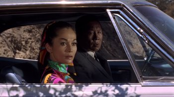 Movie still from “The Wrecking Crew” (1968), directed by Phil Karlson – A man and a woman sitting in the back of a car; Medium shot, Low angle