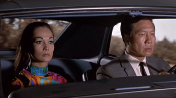 Movie still from “The Wrecking Crew” (1968), directed by Phil Karlson – A man and a woman sitting in the back seat of a car; Medium shot, Low angle