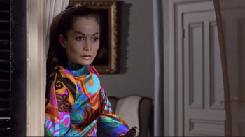Movie still from “The Wrecking Crew” (1968), directed by Phil Karlson – A young woman in a colorful dress sitting in a chair; Medium shot, High angle