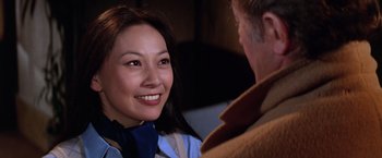 Movie still from “The Yakuza” (1974), directed by Sydney Pollack – A woman smiling at a man in a brown jacket; Close Up shot, Over the shoulder angle