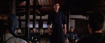 Movie still from “The Yakuza” (1974), directed by Sydney Pollack – A man standing in front of two other men; Medium shot, Low angle