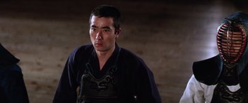 Movie still from “The Yakuza” (1974), directed by Sydney Pollack – A man wearing an overalls and a black shirt; Close Up shot, Low angle