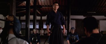 Movie still from “The Yakuza” (1974), directed by Sydney Pollack – A man holding a sword while standing in front of other people; Medium shot, Low angle