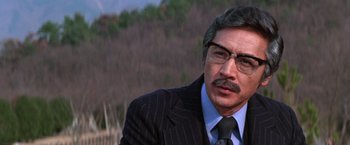 Movie still from “The Yakuza” (1974), directed by Sydney Pollack – A person wearing a suit and tie; Close Up shot, Over the shoulder angle