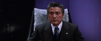 Movie still from “The Yakuza” (1974), directed by Sydney Pollack – A person wearing a suit and tie; Close Up shot, Low angle