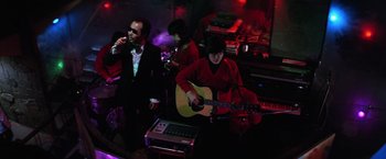 Movie still from “The Yakuza” (1974), directed by Sydney Pollack – A group of people playing instruments in a room; Medium shot, Low angle