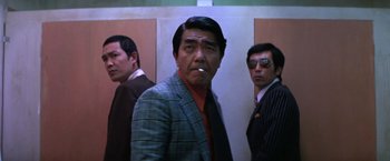 Movie still from “The Yakuza” (1974), directed by Sydney Pollack – A group of men standing next to each other in a room; Medium shot, Low angle