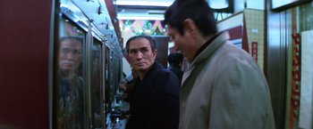Movie still from “The Yakuza” (1974), directed by Sydney Pollack – A man standing next to another man on a train; Medium shot, Low angle