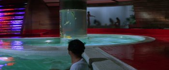 Movie still from “The Yakuza” (1974), directed by Sydney Pollack – A man sitting in a pool of water next to a fish tank; Wide shot, High angle