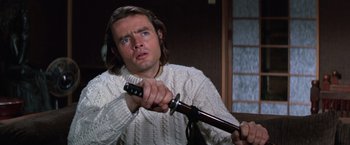 Movie still from “The Yakuza” (1974), directed by Sydney Pollack – A man in a white sweater holding a sword; Close Up shot, Low angle