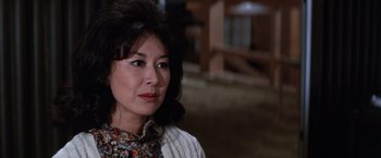 Movie still from “The Yakuza” (1974), directed by Sydney Pollack – An older woman wearing a white sweater looking at the camera; Close Up shot, Over the shoulder angle