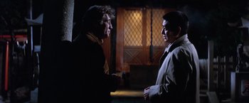 Movie still from “The Yakuza” (1974), directed by Sydney Pollack – Two men are talking in a dimly - lit room; Medium shot, Over the shoulder angle