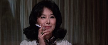Movie still from “The Yakuza” (1974), directed by Sydney Pollack – A woman smoking a cigarette while holding a cigarette holder; Close Up shot, Low angle