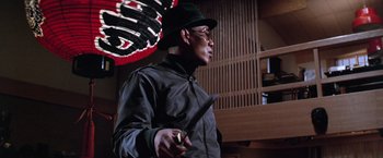 Movie still from “The Yakuza” (1974), directed by Sydney Pollack – A man holding a knife in his hand and wearing a hat; Medium shot, Low angle