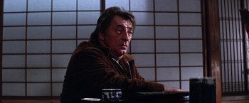 Movie still from “The Yakuza” (1974), directed by Sydney Pollack – A man sitting at a table in front of a cup; Close Up shot, Low angle