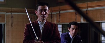Movie still from “The Yakuza” (1974), directed by Sydney Pollack – A man holding a sword while standing next to another man; Medium shot, Low angle
