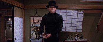 Movie still from “The Yakuza” (1974), directed by Sydney Pollack – A man in a black hat holding a sword; Medium shot, Low angle