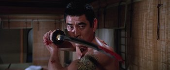 Movie still from “The Yakuza” (1974), directed by Sydney Pollack – A man holding a sword in a room; Close Up shot, Low angle