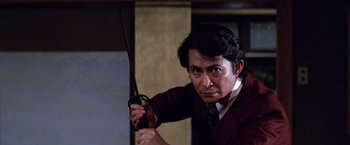 Movie still from “The Yakuza” (1974), directed by Sydney Pollack – A man holding a pair of scissors in his hand; Medium shot, Low angle