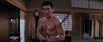 Movie still from “The Yakuza” (1974), directed by Sydney Pollack – A man holding a sword in front of another man in a room; Medium shot, Low angle