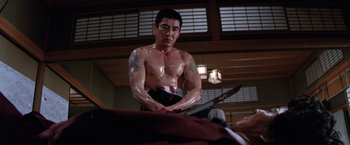 Movie still from “The Yakuza” (1974), directed by Sydney Pollack – A man with a tattoo on his chest is holding a sword in his hand; Medium shot, Low angle