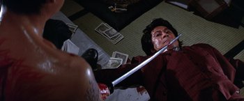 Movie still from “The Yakuza” (1974), directed by Sydney Pollack – A man holding a sword with blood on his face; Medium shot, Overhead angle