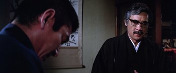Movie still from “The Yakuza” (1974), directed by Sydney Pollack – A man standing in front of a wall with his mouth wide open; Close Up shot, Over the shoulder angle