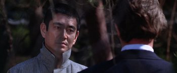 Movie still from “The Yakuza” (1974), directed by Sydney Pollack – A man in a gray jacket is talking to another man in a blue suit; Close Up shot, Over the shoulder angle