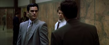 Movie still from “The Yards” (2000), directed by James Gray – A man in a suit standing next to two other men; Medium shot, Over the shoulder angle