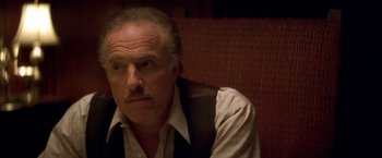 Movie still from “The Yards” (2000), directed by James Gray – An older man sitting on a couch looking at the camera; Close Up shot, High angle