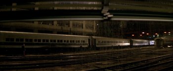 Movie still from “The Yards” (2000), directed by James Gray – A train traveling down train tracks next to a building; Extreme Wide shot, High angle