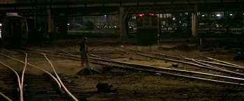 Movie still from “The Yards” (2000), directed by James Gray – A man standing in the middle of a train yard; Wide shot, High angle