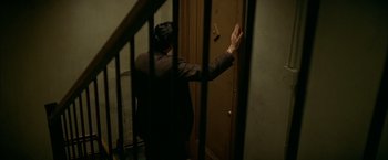 Movie still from “The Yards” (2000), directed by James Gray – A man standing in front of a door waving to someone; Wide shot, High angle