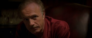 Movie still from “The Yards” (2000), directed by James Gray – An older man in a red shirt looks at the camera; Close Up shot, Low angle