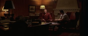 Movie still from “The Yards” (2000), directed by James Gray – A man sitting in a chair in a living room; Wide shot, Over the shoulder angle