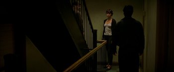 Movie still from “The Yards” (2000), directed by James Gray – A woman standing next to a railing in a dark room; Medium shot, High angle