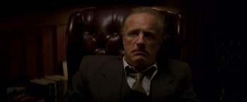 Movie still from “The Yards” (2000), directed by James Gray – An older man in a suit and tie sitting in a chair; Close Up shot, Low angle