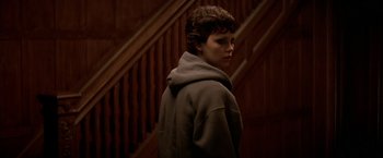 Movie still from “The Yards” (2000), directed by James Gray – A woman standing in front of a wooden staircase; Medium shot, High angle