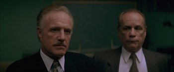 Movie still from “The Yards” (2000), directed by James Gray – A man in a suit and tie standing next to another man in a suit and tie; Close Up shot, Low angle