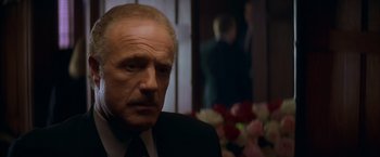 Movie still from “The Yards” (2000), directed by James Gray – A man in a suit and tie in front of flowers; Close Up shot, Low angle