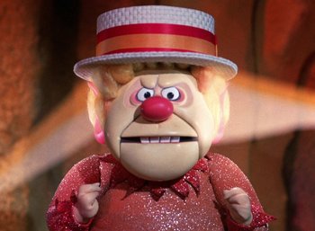 Movie still from “The Year Without a Santa Claus” (1974), directed by Jules Bass – The face of a doll wearing a top hat; Close Up shot, Low angle