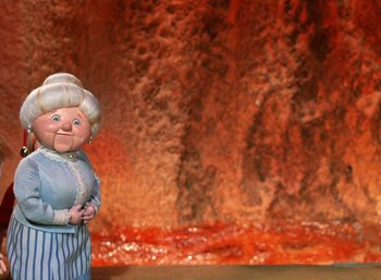 Movie still from “The Year Without a Santa Claus” (1974), directed by Jules Bass – An old woman doll standing in front of a fire pit; Medium shot, Low angle