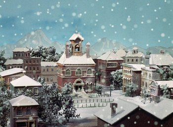 Movie still from “The Year Without a Santa Claus” (1974), directed by Jules Bass – An old town with a clock tower in the middle of it; Extreme Wide shot, High angle
