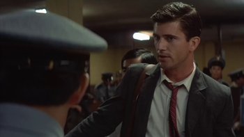 Movie still from “The Year of Living Dangerously” (1982), directed by Peter Weir – A man wearing a suit and tie talking to a man wearing a hat; Close Up shot, Over the shoulder angle