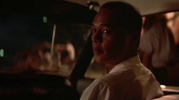 Movie still from “The Year of Living Dangerously” (1982), directed by Peter Weir – A person sitting in a car at night; Close Up shot, Low angle