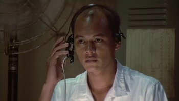 Movie still from “The Year of Living Dangerously” (1982), directed by Peter Weir – A man wearing a white shirt holding up a phone; Close Up shot, Low angle