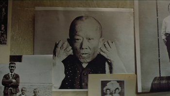 Movie still from “The Year of Living Dangerously” (1982), directed by Peter Weir – An old photo of an older man covering his ears with his hands; Extreme Close Up shot, High angle